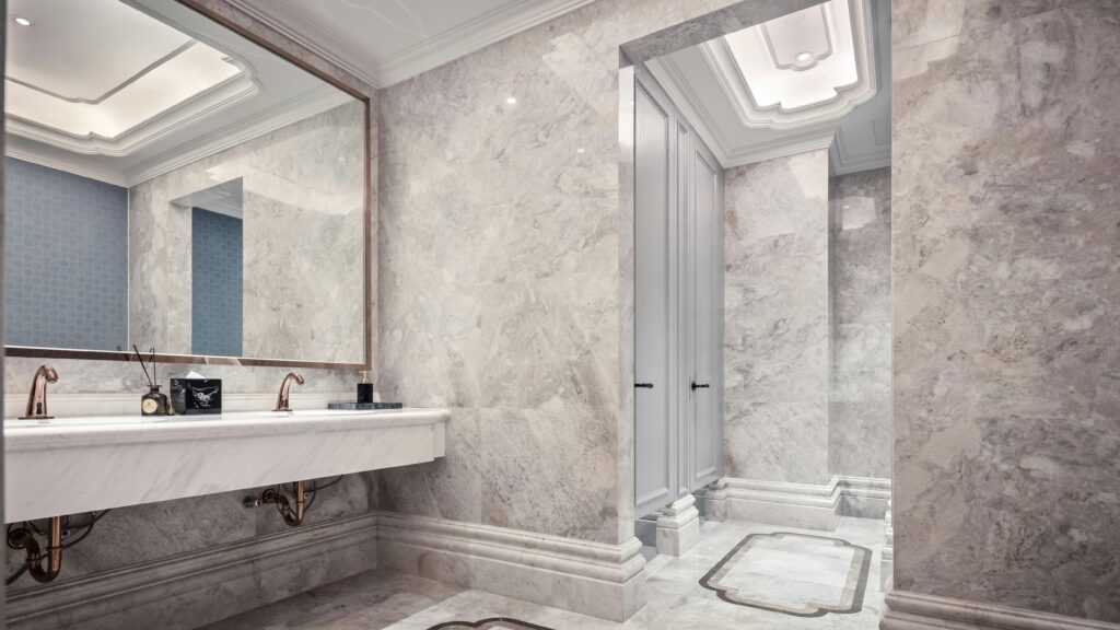 Luxurious bathroom interior with marble walls, large mirror, and modern fixtures, showcasing elegant design.